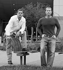 Black and white photograph of two men standing in front of an office building.