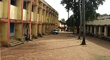 Two buildings, separated by a dirt road and trees